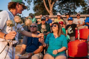 Baseball player gives roses to fans in the stands.