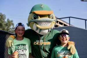 Two boys with a mascot, Cape Catfish, at a baseball event. One boy holds a can.
