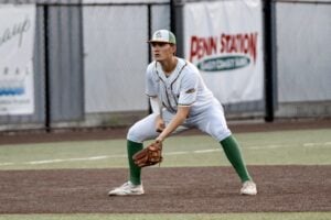 Baseball player in uniform crouching on field, ready to catch.