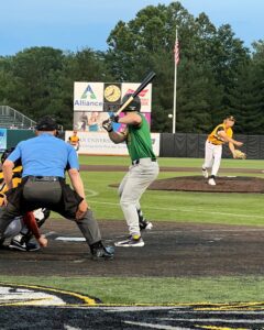 Baseball batter in green and gray swings at a pitch from a pitcher in yellow and white.