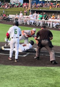 Baseball players and umpire at home plate, one player sliding into base.