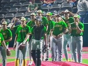 Baseball players in green and yellow uniforms on the field with a catcher in gear.