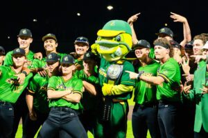 Baseball team and mascot celebrate victory, wearing green uniforms and championship belt.